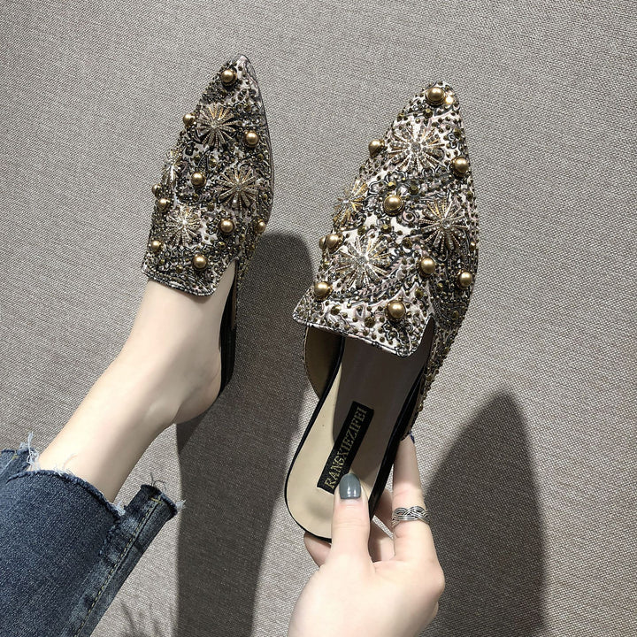 Modische Damen-Slipper für den Sommer. Flache Schuhe im römischen Stil mit eleganten Metall-Verzierungen.