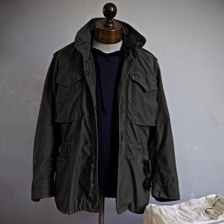 Mann trägt schwarze robuste Herren Feldjacke, ideal für Outdoor. Strapazierfähig & wetterfest für jede Freizeit.