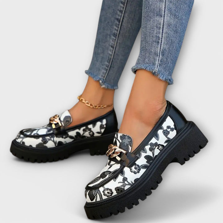 Schwarze Damen Mokassins mit floralem Muster, dicker Sohle und eleganter Metallschnalle. Bequeme Sommerschuhe.