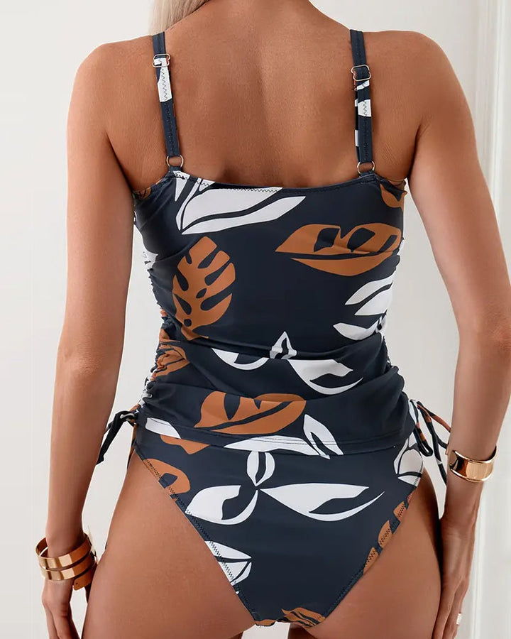 Detailaufnahme: Gerüschter Kordelzug am figurschmeichelnden Tankini-Oberteil. Marineblauer Damen Badeanzug mit Blättern.