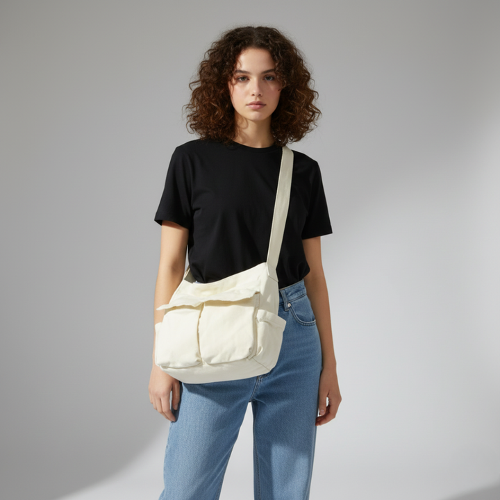 Eine Person trägt eine weiße Canvas Messenger Bag lässig über der Schulter, urbaner Stil.