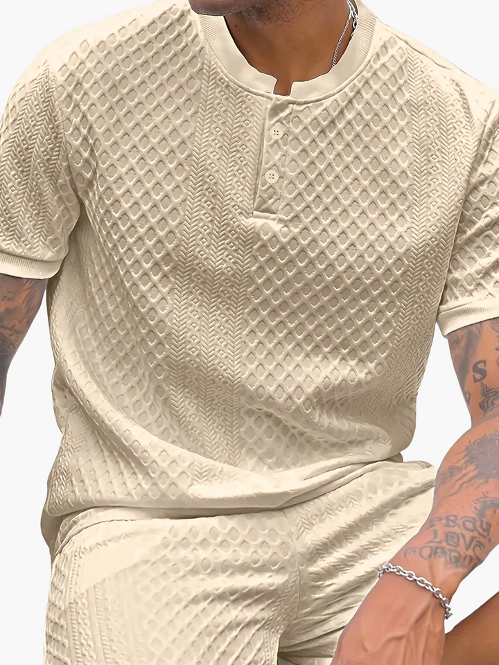 Junger Mann trägt das moderne Herren Sommer-Outfit aus T-Shirt und Shorts im Freien.
