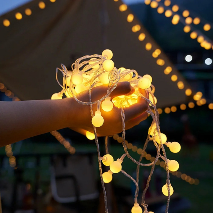 Solar-LED-Lichterkette 9.5m mit 50 LEDs am Zaun. Wasserdichte Dekobeleuchtung schafft warme Gartenatmosphäre.