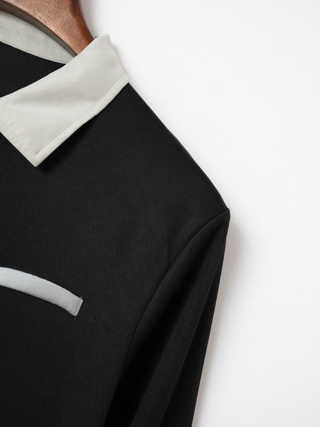 Nahaufnahme des Kontrastkragens eines pinkfarbenen Herren Langarmpolos, unterstreicht den eleganten Stil.