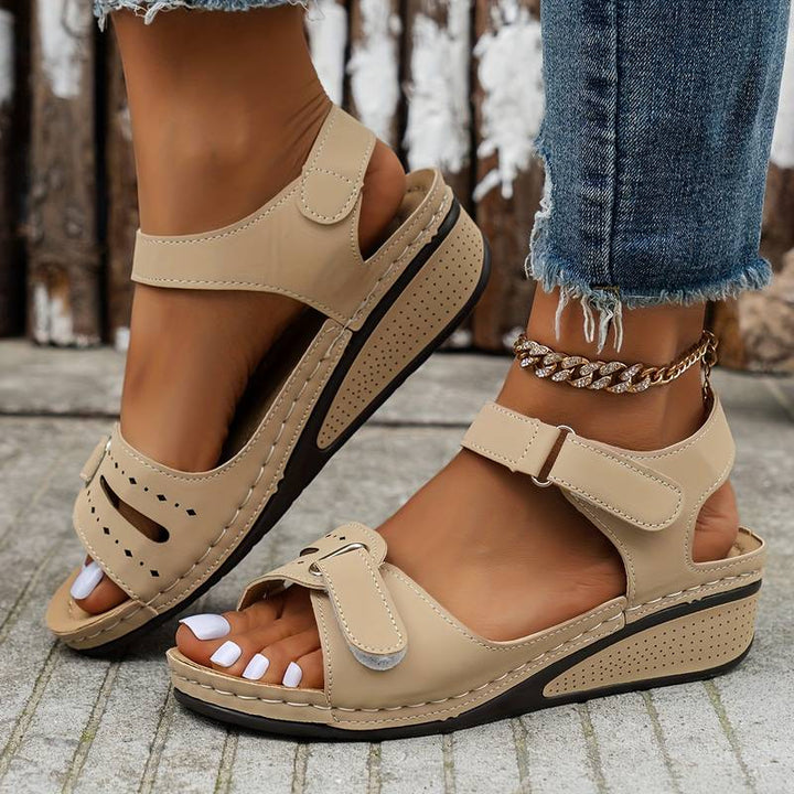 Nahaufnahme: Orthopädische rote Damensandalen mit weicher Innensohle und starker Fußgewölbestütze.