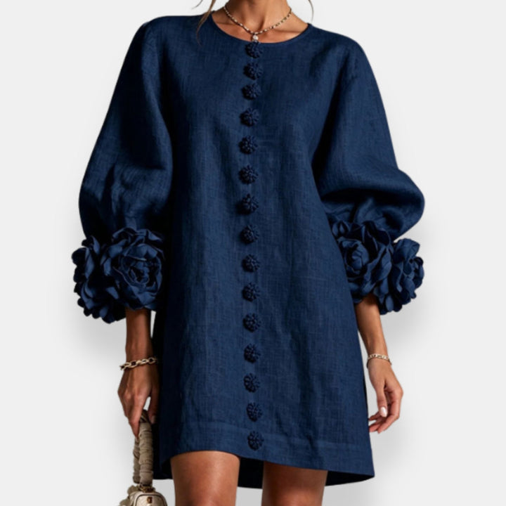 Ausschnittdetail eines eleganten Damen Sommerkleides mit Blütenrelief und Knopfverschluss.