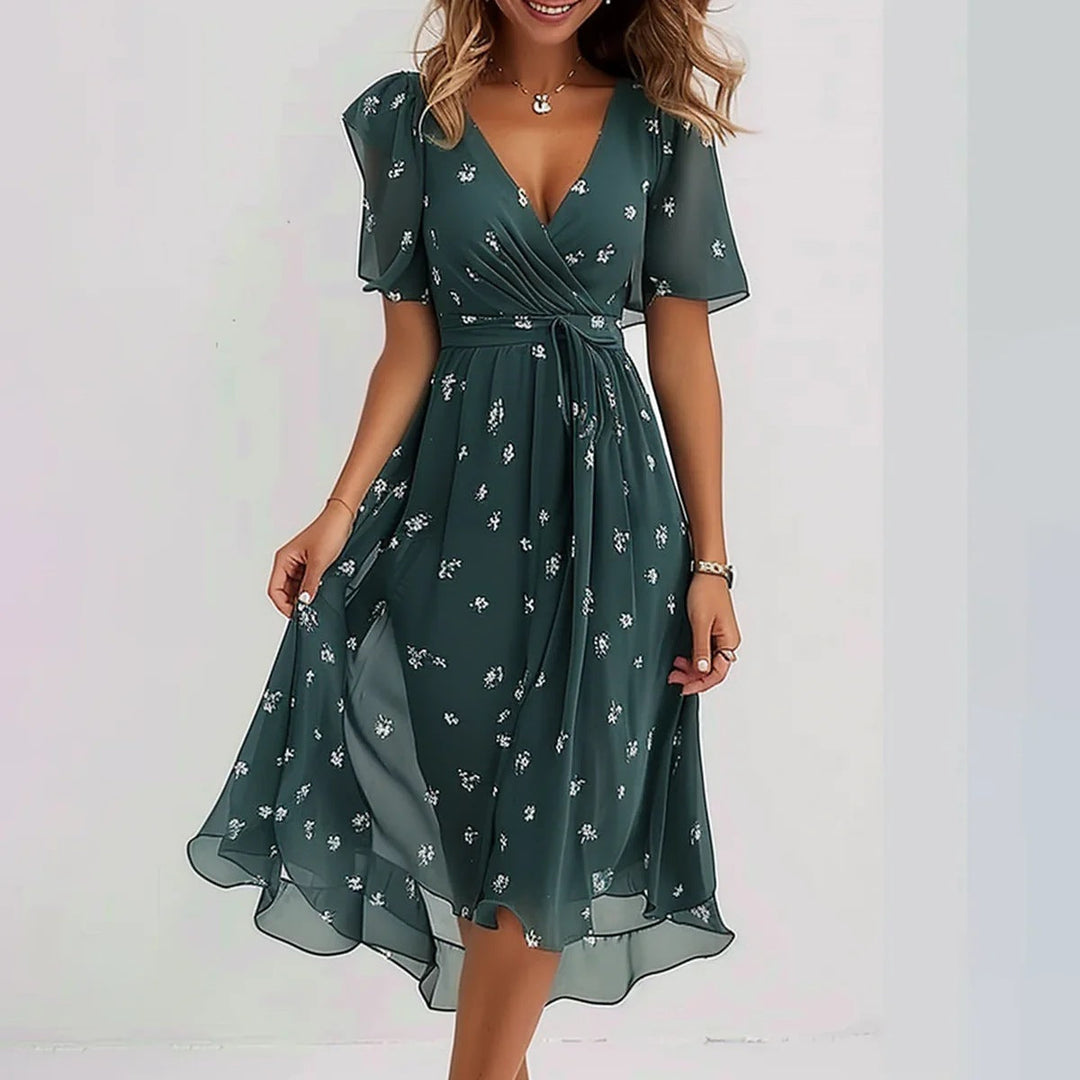 Frau trägt bedrucktes V-Ausschnitt Sommerkleid im A-Linien-Schnitt. Fließendes Urlaubskleid für warme Tage am Strand.