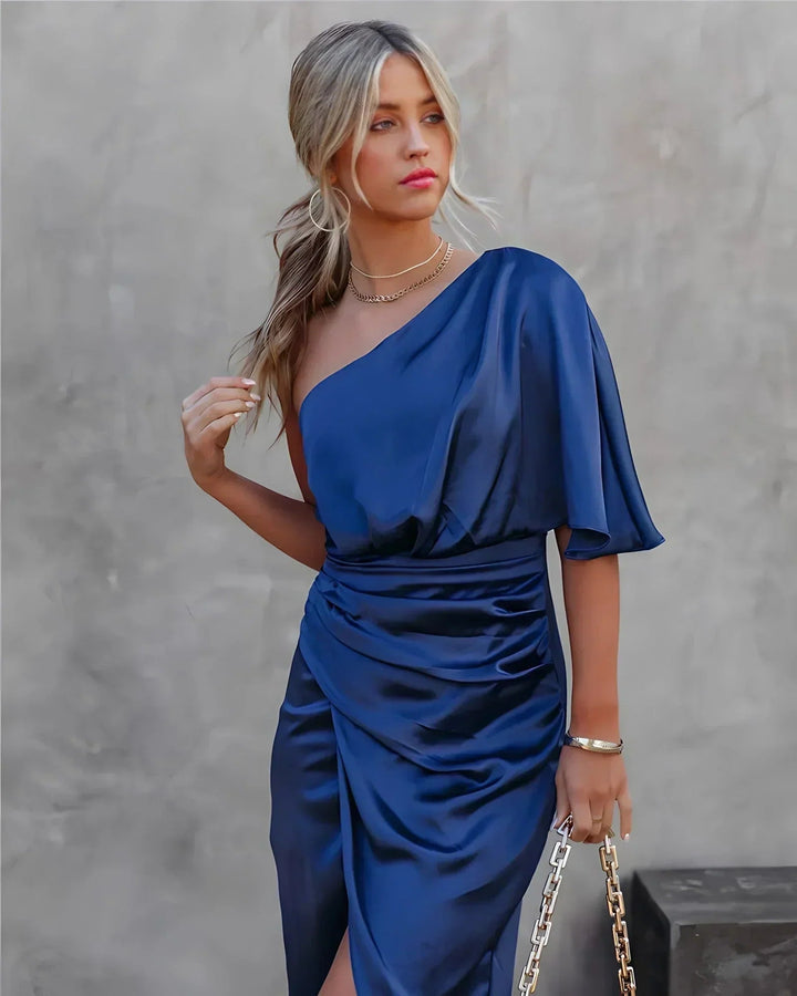 Seitliche Ansicht des eleganten asymmetrischen Damen Midikleides, das die fließende Silhouette betont.