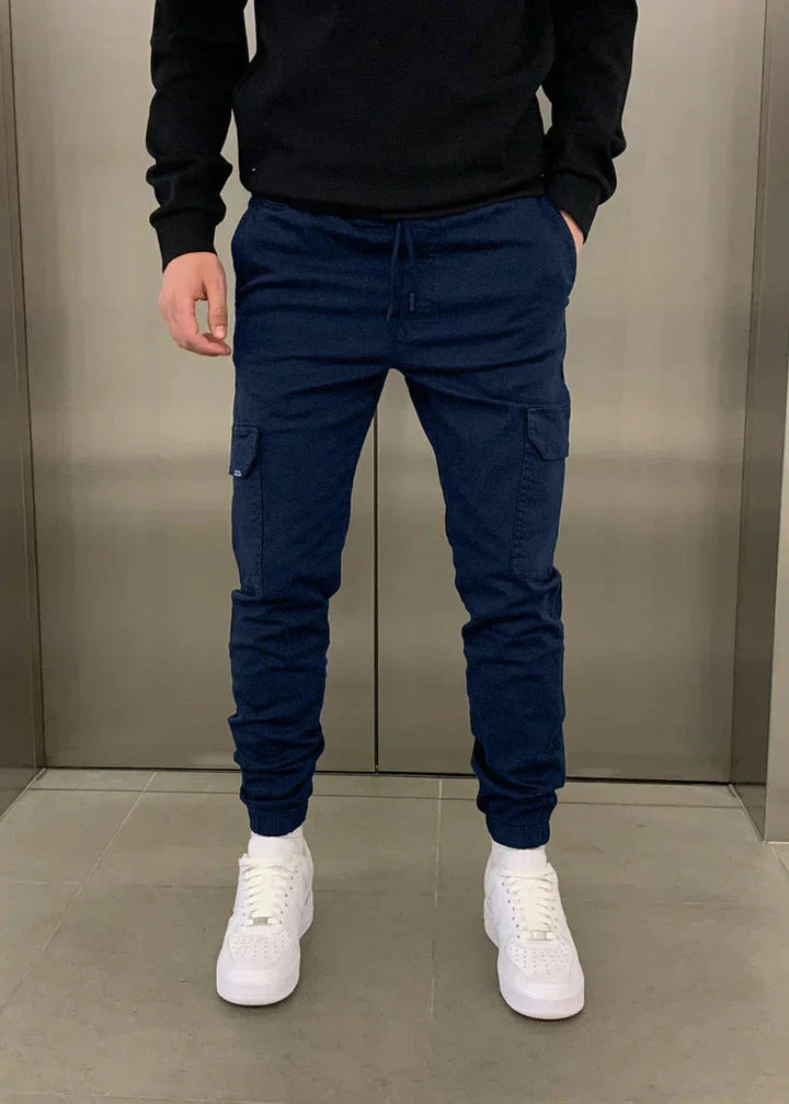 Mann trägt bequeme Herren Cargo-Jogginghose mit Seitentaschen, ideal für Outdoor- & Freizeitaktivitäten. Lässiger Stil.