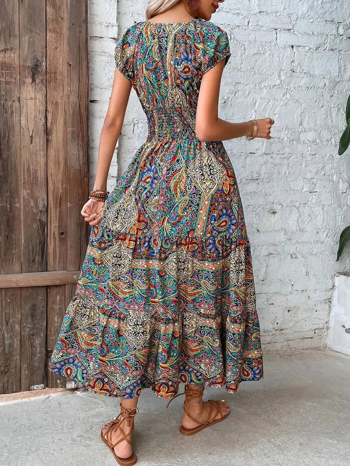 Elegantes Maxikleid für Damen mit tiefem V-Ausschnitt und betonter hoher Taille. Kurze Ärmel, abstraktes Design.