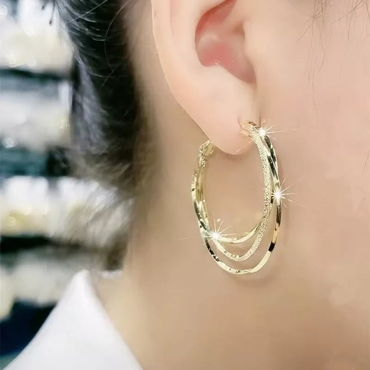 Moderne runde mehrschichtige Creolen für Damen, stilvoller hypoallergener Ohrschmuck als Accessoire.