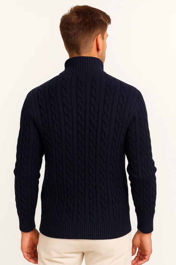Mann trägt einen tiefblaugrünen Herrenpullover mit Zopfmuster und Reißverschluss im Frühling.