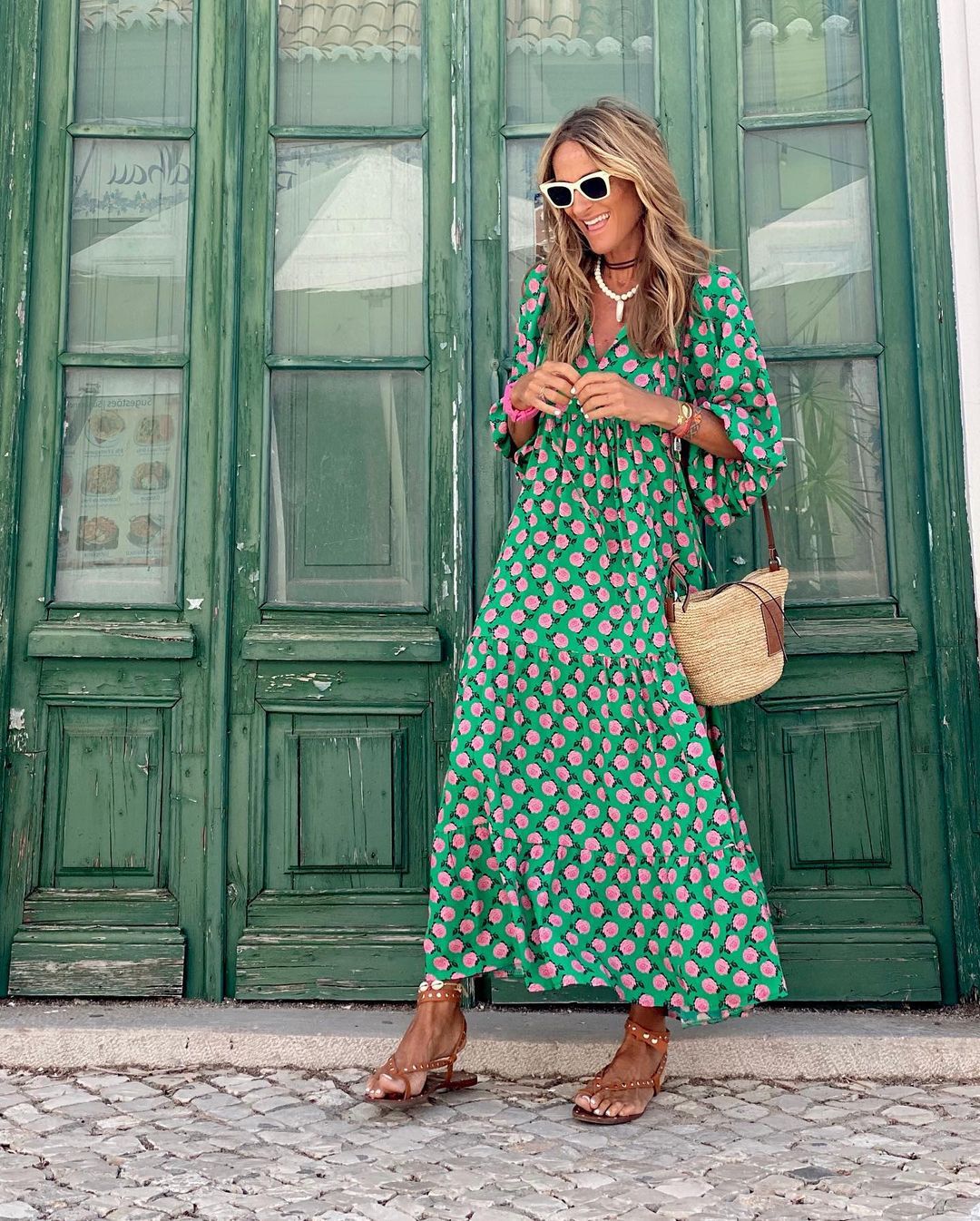 Model trägt elegantes grünes Maxikleid mit geometrischem Muster, V-Ausschnitt und Bindegürtel. Sommerlich.