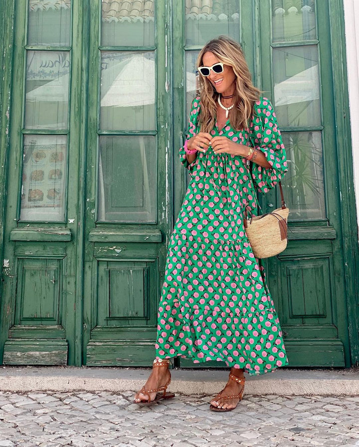 Model trägt elegantes grünes Maxikleid mit geometrischem Muster, V-Ausschnitt und Bindegürtel. Sommerlich.