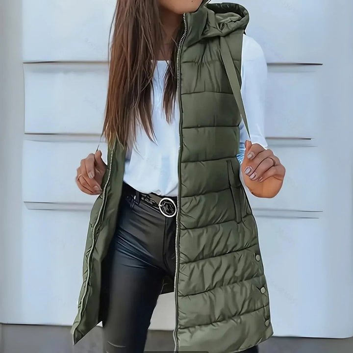 Elegante, lange ärmellose Pufferweste für Damen, mit Kapuze, als leichte Oberbekleidung für kühle Tage geeignet.
