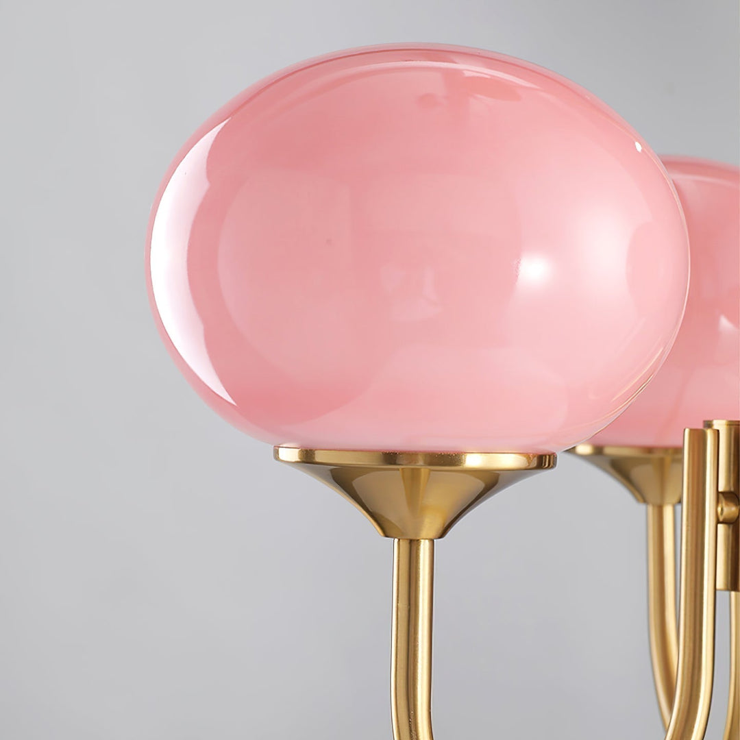 Moderner Roségold-Kronleuchter mit runden Glas-Lampenschirmen; warme Wohnzimmerbeleuchtung.
