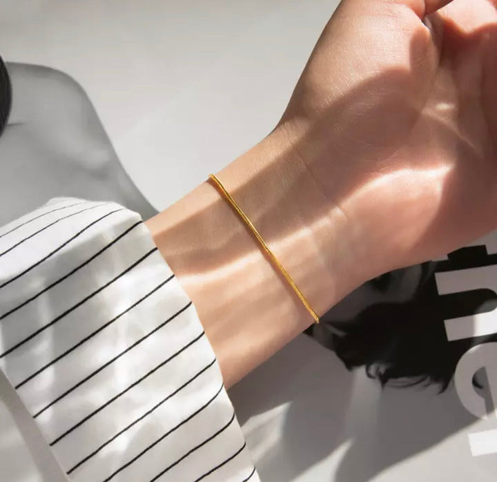 Damenarmband: Minimalistisches goldfarbenes Schlangenketten-Armband aus Edelstahl elegant am Handgelenk.