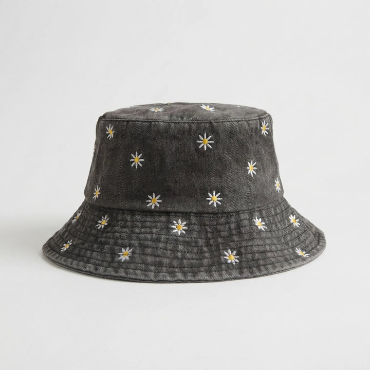 Detailaufnahme: Gänseblümchen-Stickerei auf cremefarbenem Unisex Baumwoll-Fischerhut, Vintage-Stil.