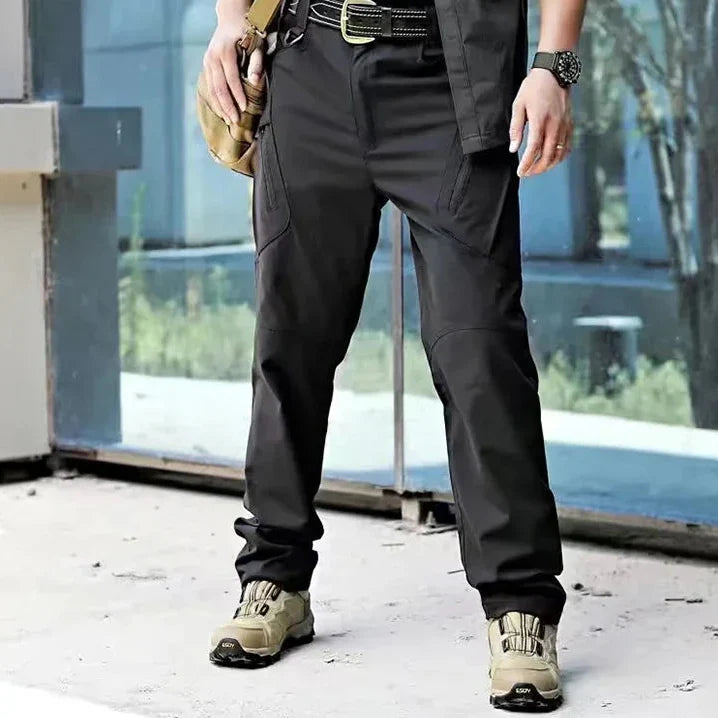 Stehender Mann trägt die funktionelle Traxlon Outdoorhose, bereit für Abenteuer in der Natur.