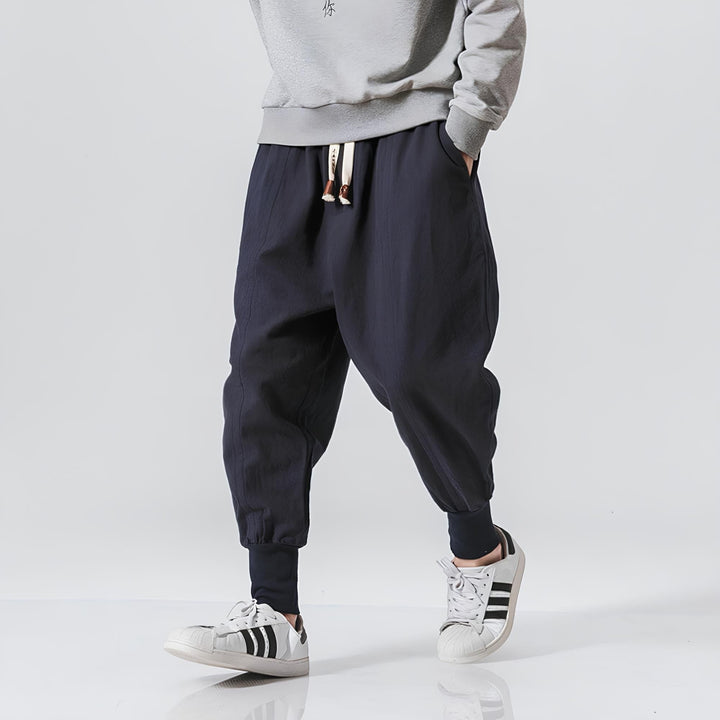 Mann trägt bequeme Streetwear-Jogger mit tiefem Schritt. Ideale Freizeithose für urbanen Style.