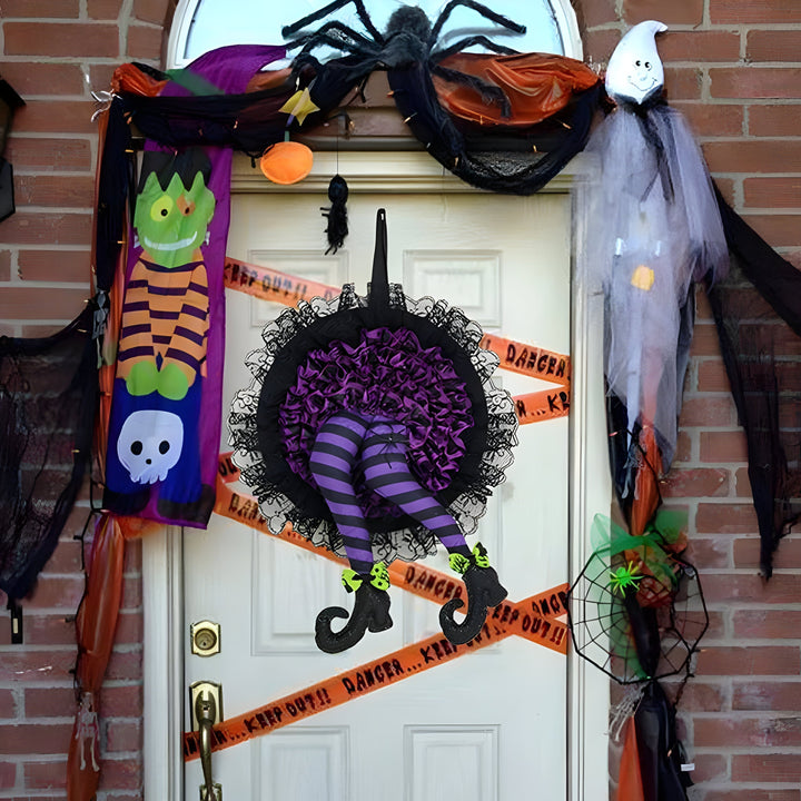 Detailaufnahme des Halloween Hexenkranzes mit lila Schleife, orange Elementen & den gestreiften Hexenbeinen.