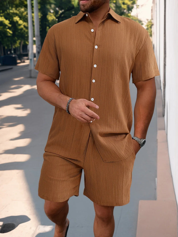Mann trägt helles Herren Kurzarmhemd & Shorts Set. Lässiger Sommer Look, ideal für Freizeit & Urlaub.