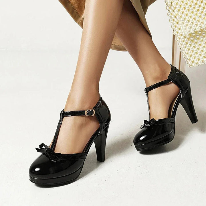 Klassische schwarze Damen Pumps mit T-Riemen, goldener Knöchelschnalle und bequemem Blockabsatz.