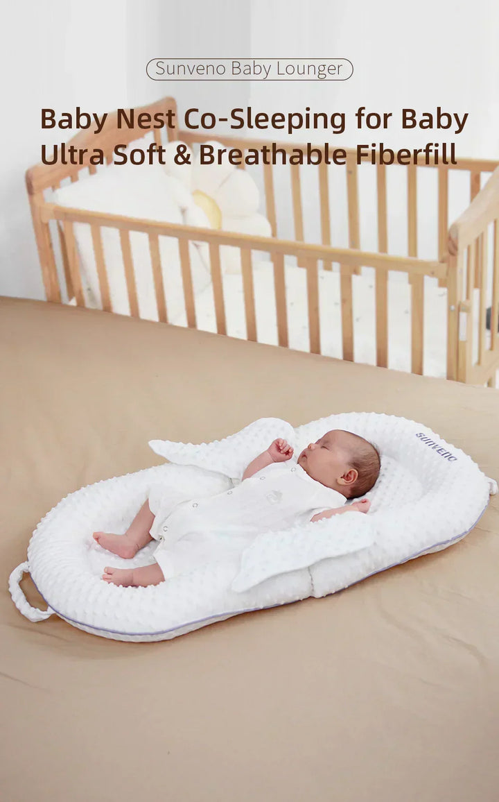 Glückliches Baby schläft geborgen im ergonomischen Babynest mit weicher Polsterung und Rückenstütze.