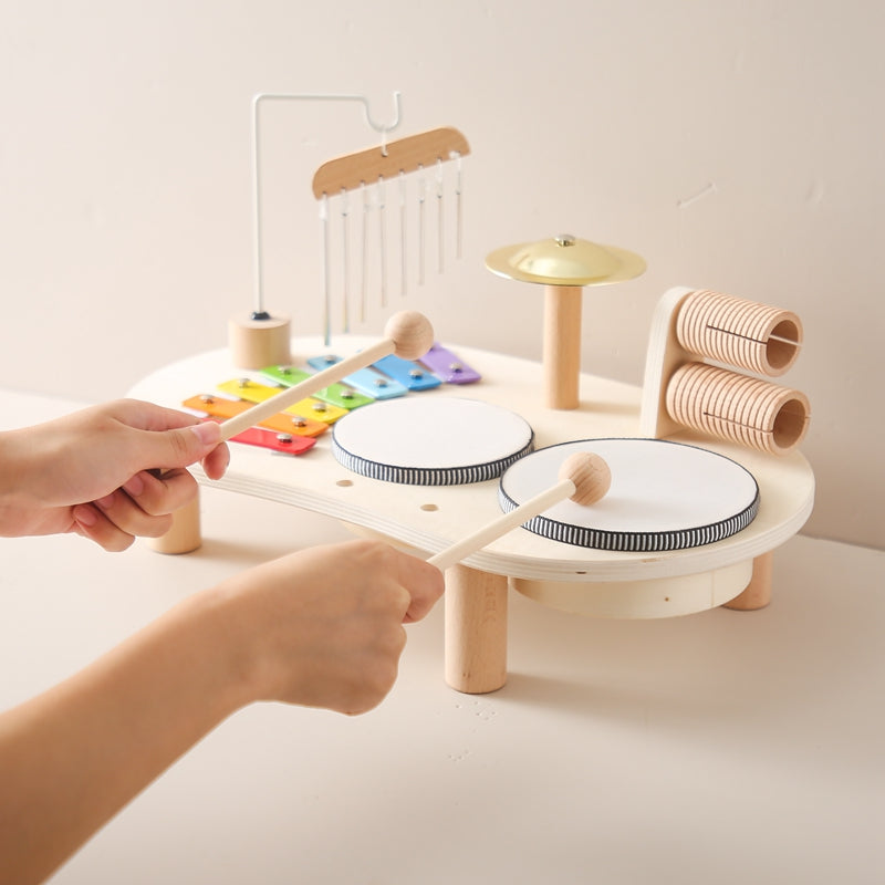 Zwei Trommeln und ein Becken aus Holz, integriert in ein Kinder Musikspielzeug, für erste rhythmische Erfahrungen.