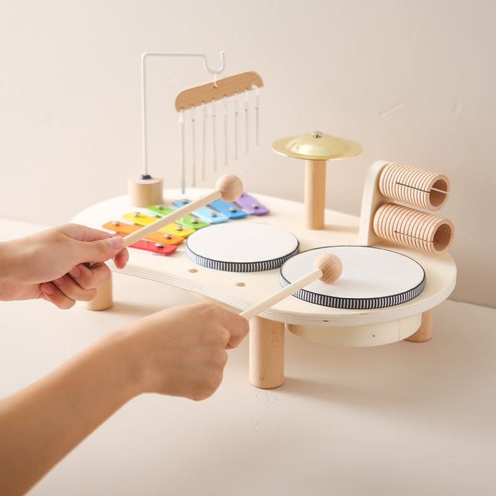 Zwei Trommeln und ein Becken aus Holz, integriert in ein Kinder Musikspielzeug, für erste rhythmische Erfahrungen.