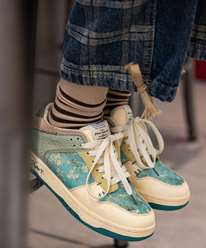 Nahaufnahme der Kunst-Sneaker mit filigranem Mandelblüten-Print, hochwertige Textur und leuchtende Farben.