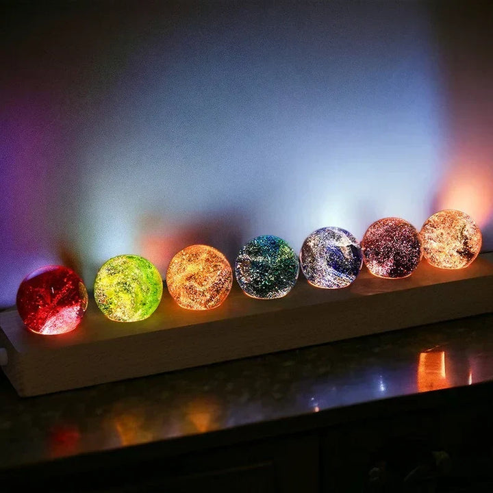 Nahaufnahme der Aurasphere Kristallkugel Leuchte, siebenteilig, mit sanftem Galaxie-Licht und Holz-Basis.