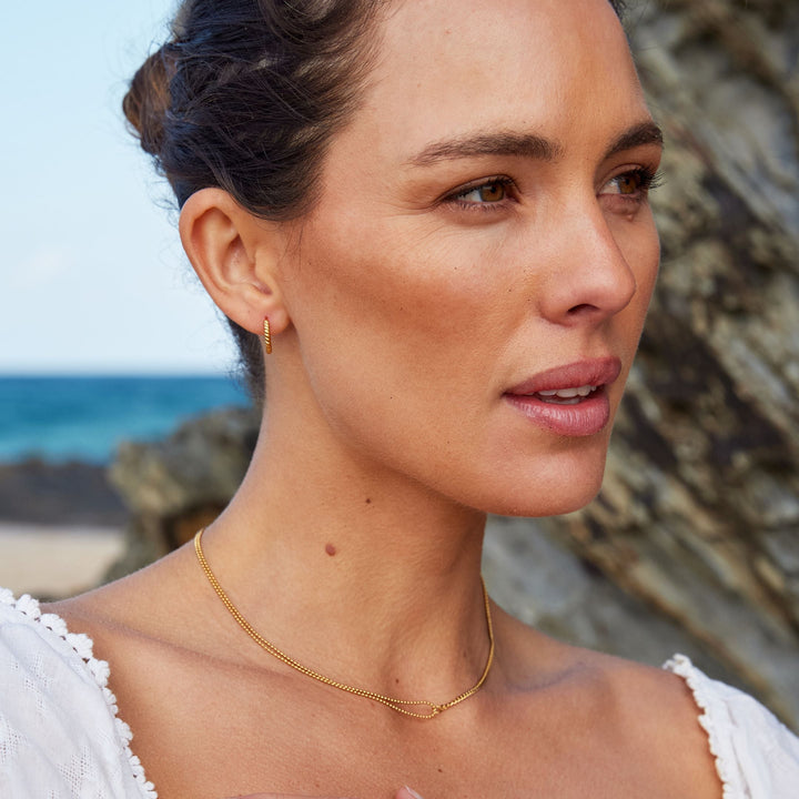 Nahaufnahme: Goldene, gedrehte Edelstahl-Creolen für Damen, detaillierter, eleganter Schmuck.