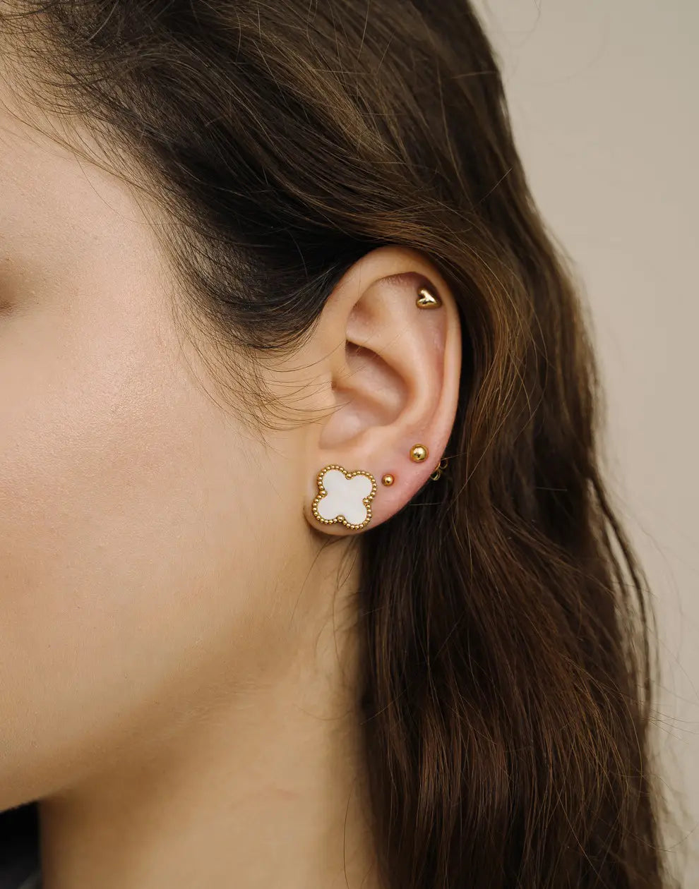 Detailaufnahme der vergoldeten Kleeblatt-Ohrstecker mit edlen Perlen; ein stilvolles Accessoire für Damen.