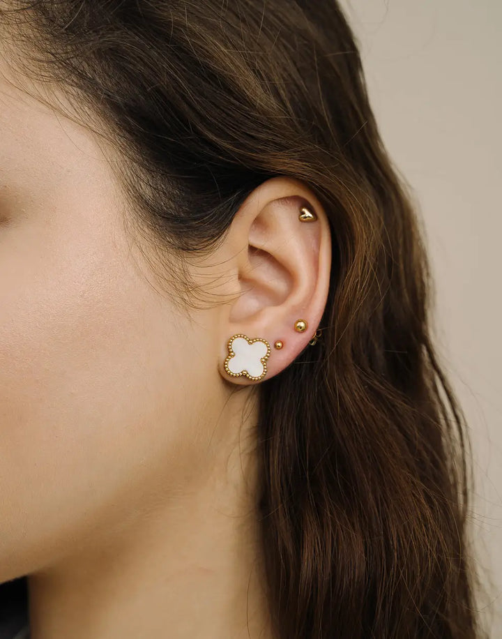 Detailaufnahme der vergoldeten Kleeblatt-Ohrstecker mit edlen Perlen; ein stilvolles Accessoire für Damen.