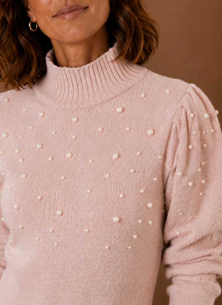 Nahaufnahme: Elegante Perlenstickerei am hohen Ausschnitt eines rosa Damen Strickkleides. Feminines Detail.