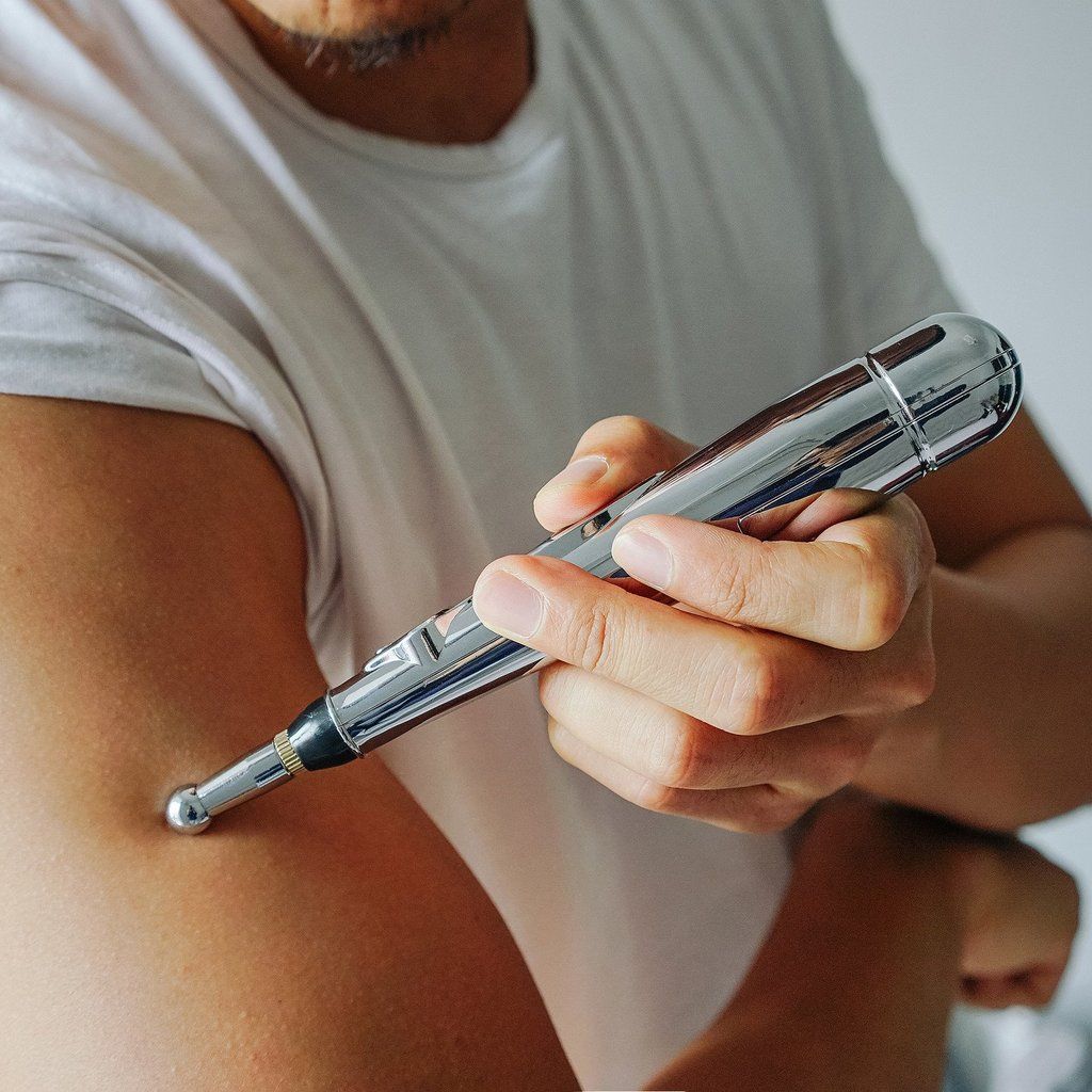 Tragbarer Akupunktur-Massage-Stift in Hand gehalten. Ideal für nadelnfreie Schmerzlinderung & Entspannung unterwegs.
