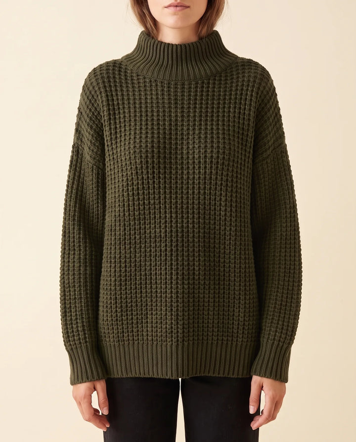 Ganze Figur: Frau trägt modischen, bequemen Oversized Rollkragenpullover für Damen.