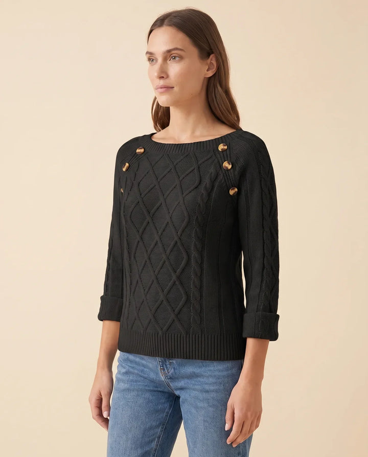 Nahaufnahme des Zopfmusters und der Schulterknöpfe am eleganten Damen Strickpullover, hochwertige Strickware.