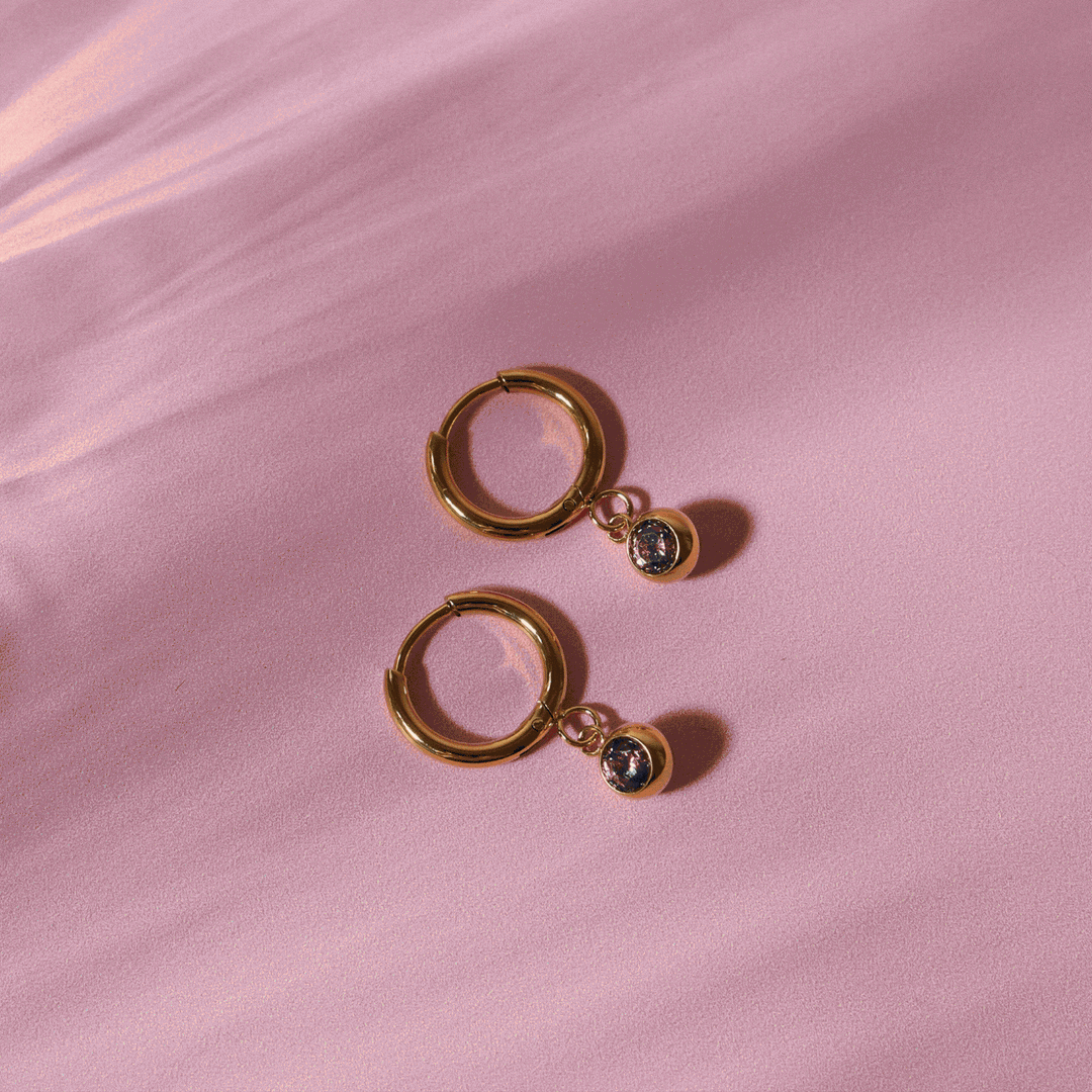 Exklusive Huggie Creolen in Gold mit schimmerndem Zirkonia und Geburtsstein. Perfekt für Damen.