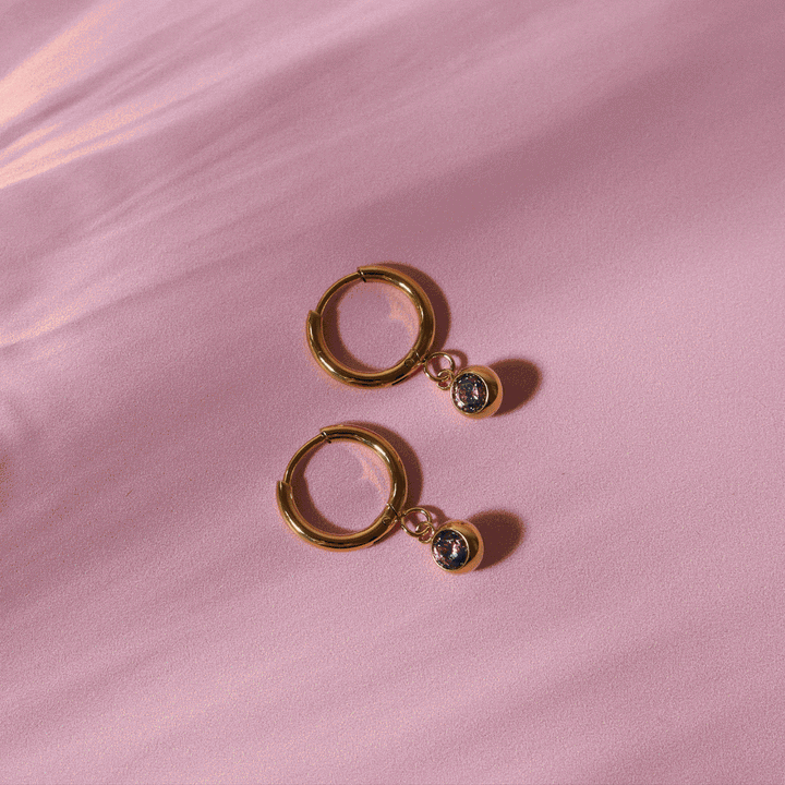 Exklusive Huggie Creolen in Gold mit schimmerndem Zirkonia und Geburtsstein. Perfekt für Damen.