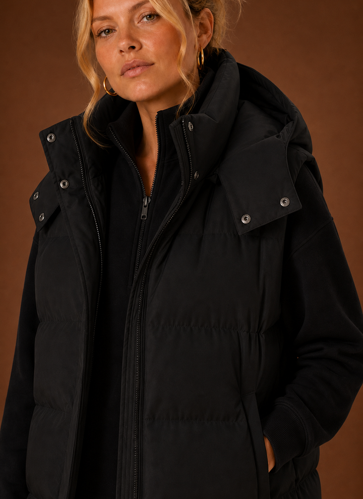 Lässige schwarze Damen Kapuzenweste, oversized. Warme ärmellose Steppweste als Übergangsjacke für Winter.