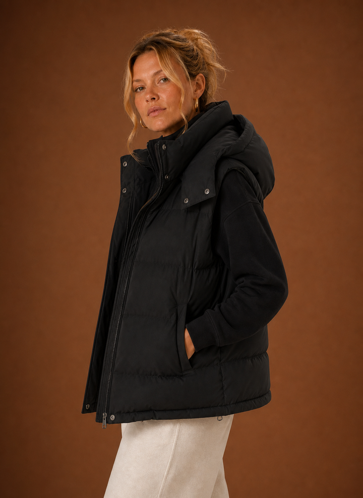 Schwarze wattierte Damen Steppweste, oversized mit Kapuze. Modische, bequeme ärmellose Jacke für Herbst.