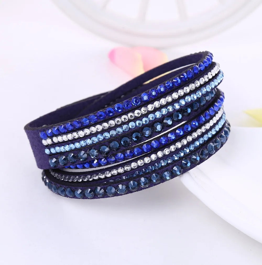 Nahaufnahme eines funkelnden Unisex Glitzerarmbands, mehrschichtig, detailreich mit schimmernden Strasssteinen.