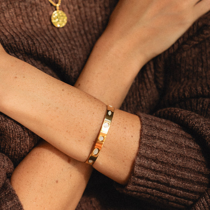 Armreif aus Gold mit Perlmutt für Damen, am Handgelenk getragen. Wasserfest und perfekt für den Alltag.