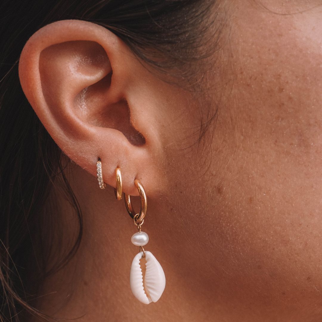 Exklusiver Damen Schmuck: Gold Creolen mit Kauri Muschel und Süßwasserperle. Wasserdicht und hypoallergen.