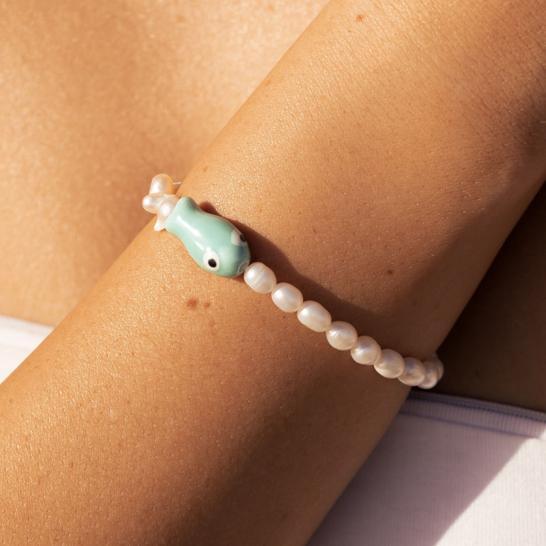 Damen Gold Armband mit edlem Fisch-Anhänger & glänzenden Süßwasserperlen. Maritimer Damenschmuck aus Edelstahl.