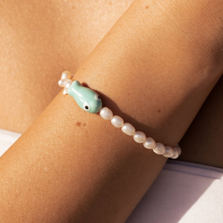 Damen Gold Armband mit edlem Fisch-Anhänger & glänzenden Süßwasserperlen. Maritimer Damenschmuck aus Edelstahl.