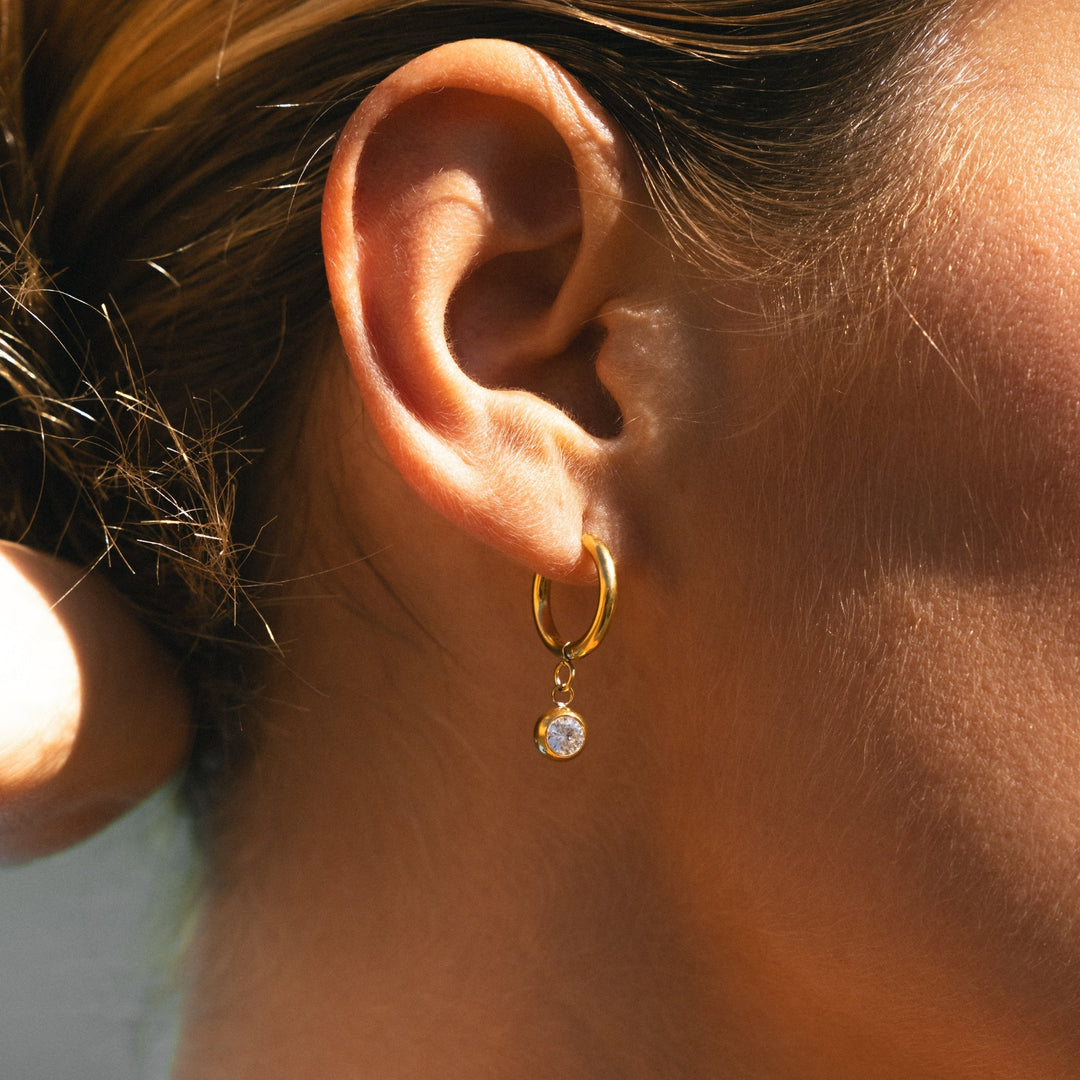 Damen Huggie Creolen Gold mit Zirkonia Geburtsstein Anhänger. Wasserdicht & hypoallergen.