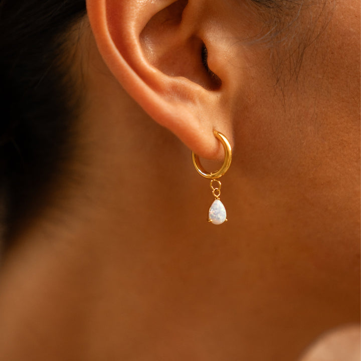 Detailansicht des schimmernden Opal-Tropfenanhängers an einer goldenen Huggie Creole für Damen, Edelstahlschmuck.